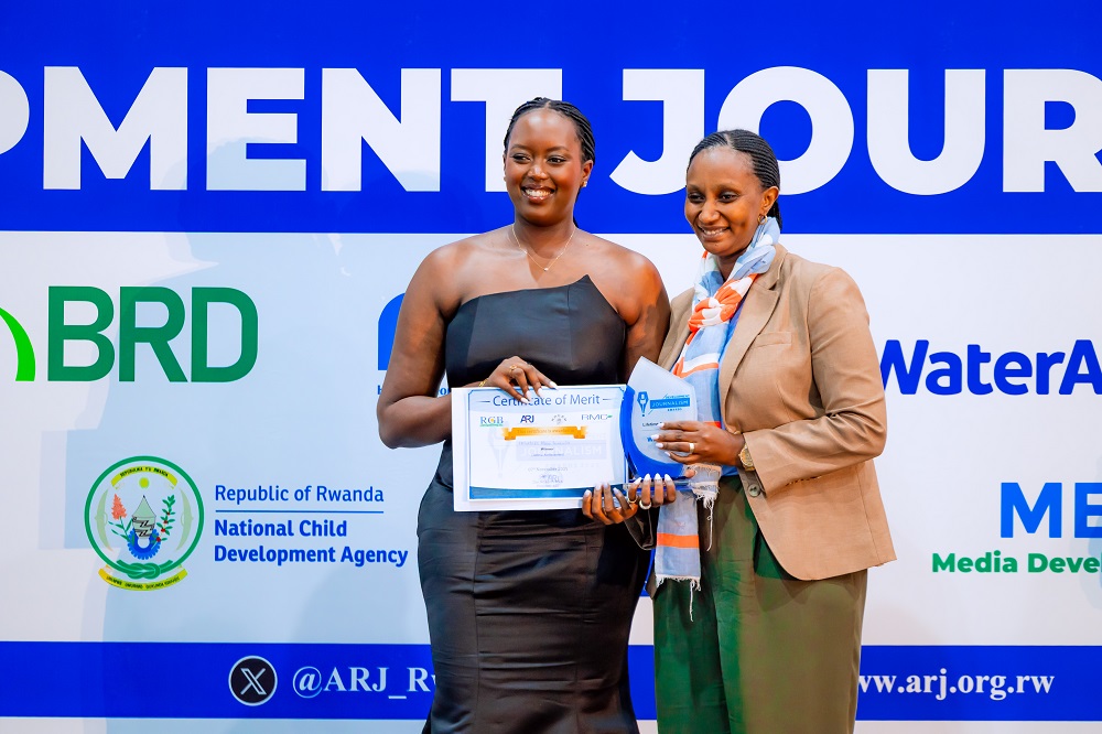 Mutesi Scovia ashyikiriza umukobwa wa Ingabire Marie Immaculee igihembo cy'uwakoze ibikorwa by'indashyikirwa mu itangazamakuru