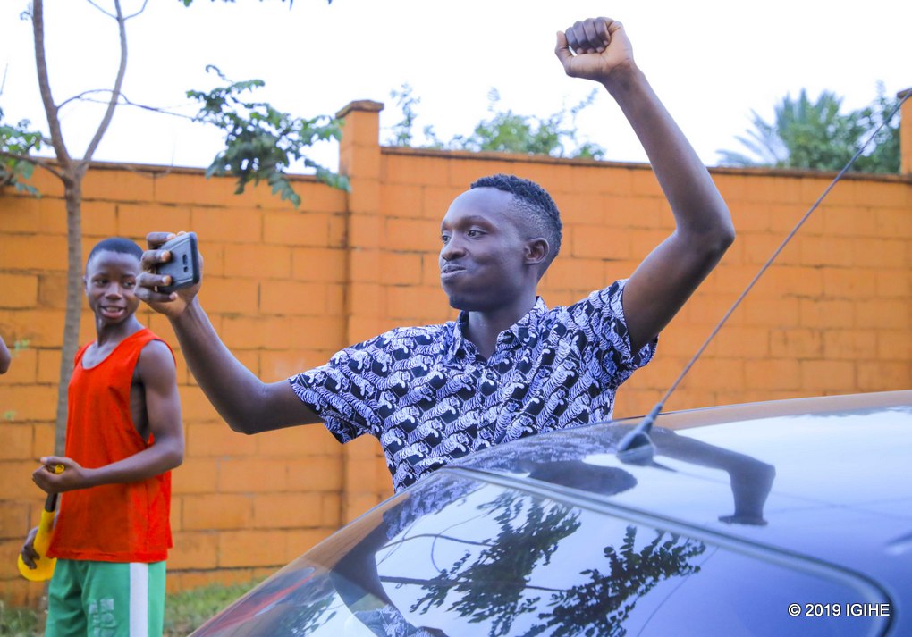 Rutahizamu Nizeyimana Djuma utakinnye umukino w'ejo yicaye mu idirishya ry'imodoka agenda afata amashusho na telefoni