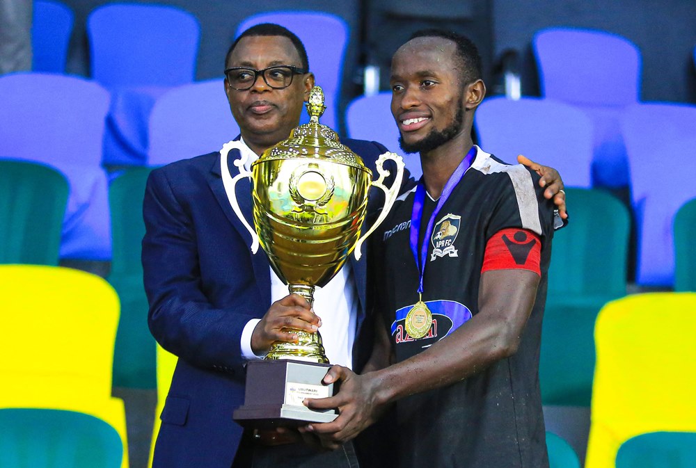 Manzi Thierry ashyikiriza Perezida w'Icyubahiro wa APR FC, Gen James Kabarebe, igikombe cy'Intwari iyi kipe yegukanye mu 2020
