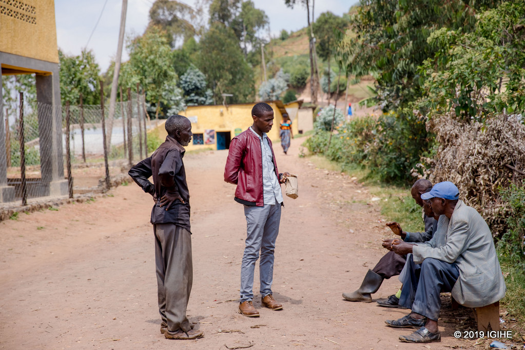 Tuyambaze Jean de Dieu aganira n'abaturage bo mu gace yavutsemo. Muri bo harimo Rurangirana Emmanuel (wambeye ishati y'umukara) wanyuzwe n'iterambere abana babo babegereje