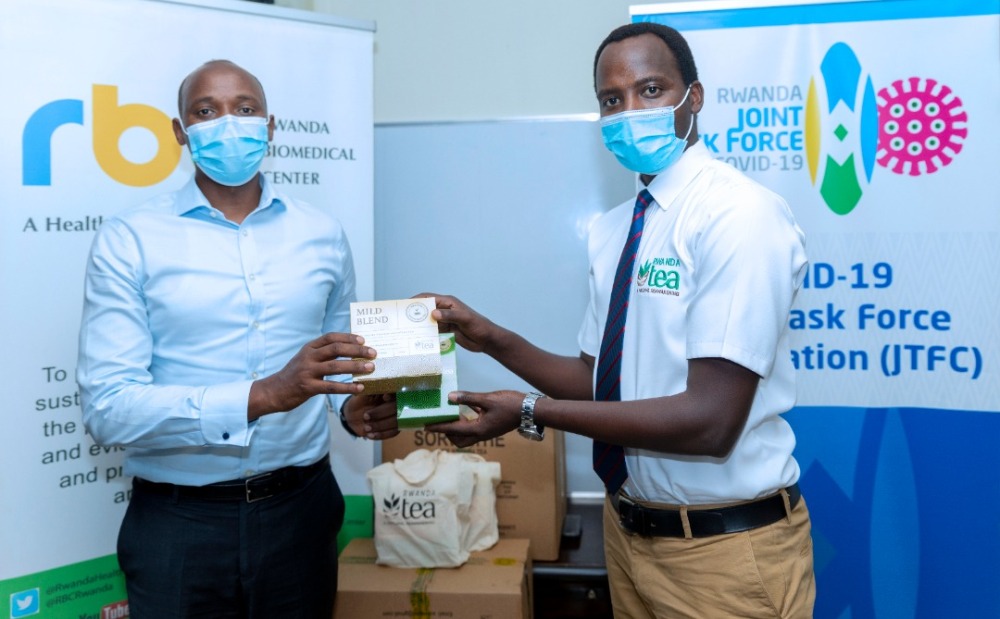 Umuyobozi wa RBC, Dr. Nsanzimana Sabin (ibumoso) ashyikirizwa n'Umuyobozi ushinzwe guteza Imbere Ibihingwa Ngengabukungu muri NAEB, Nkurunziza Issa, icyayi cyagenewe itsinda ryita ku barwayi ba Coronavirus