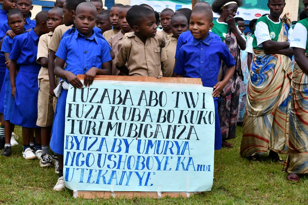 Abana bari bafite ibyapa biriho ubutumwa bushishikariza imiryango kubana neza