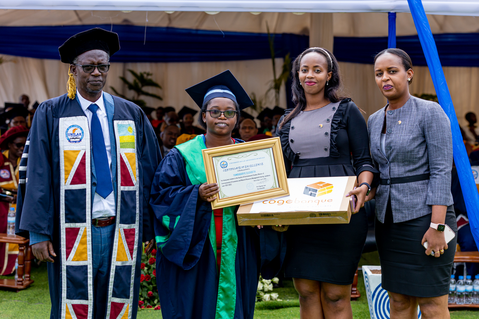 Umukozi ushinzwe Itangazamakuru n'Itumanaho muri Cogebanque, Kwizera Carmella (uwa kabiri iburyo), ashyikiriza umwe mu banyeshuri bitwaye neza mudasobwa