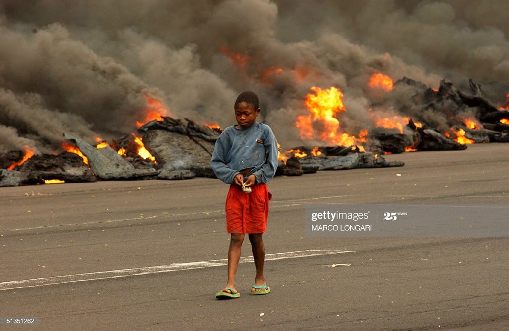 Ifoto igaragaza umwana agenda hafi y'umiriro n'ibikoma bya Nyiragongo ubwo byisukaga mu mujyi wa Goma mu 2002