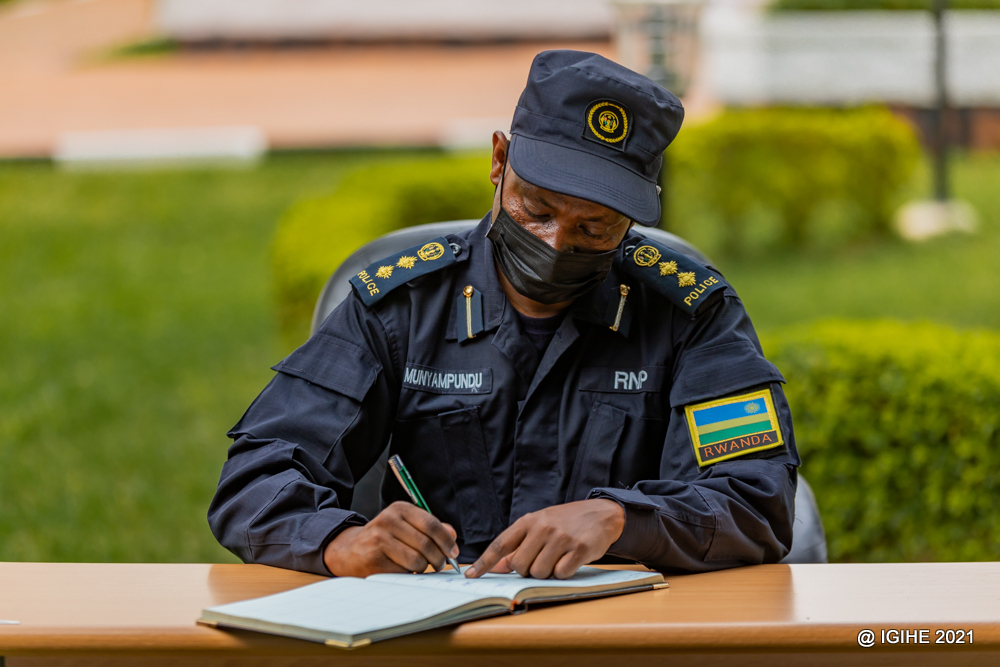 Umuyobozi w'iri tsinda ry'abanyeshuri 45 asinya mu gitabo cy'abashyitsi