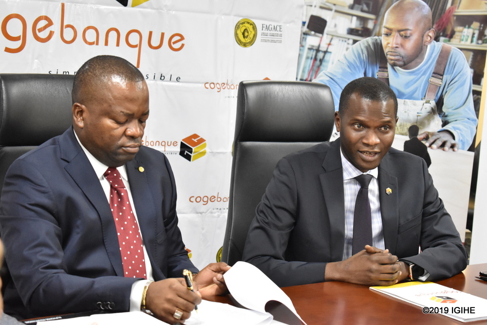 Umuyobozi Mukuru wa FAGACE, Basile Tchakounte n’Umuyobozi Mukuru wa Cogebanque, Cherno Gaye bashyira umukono ku masezerano azafasha Yego Innovision kwishyura ingendo kuri moto hakoreshejwe ikoranabuhanga