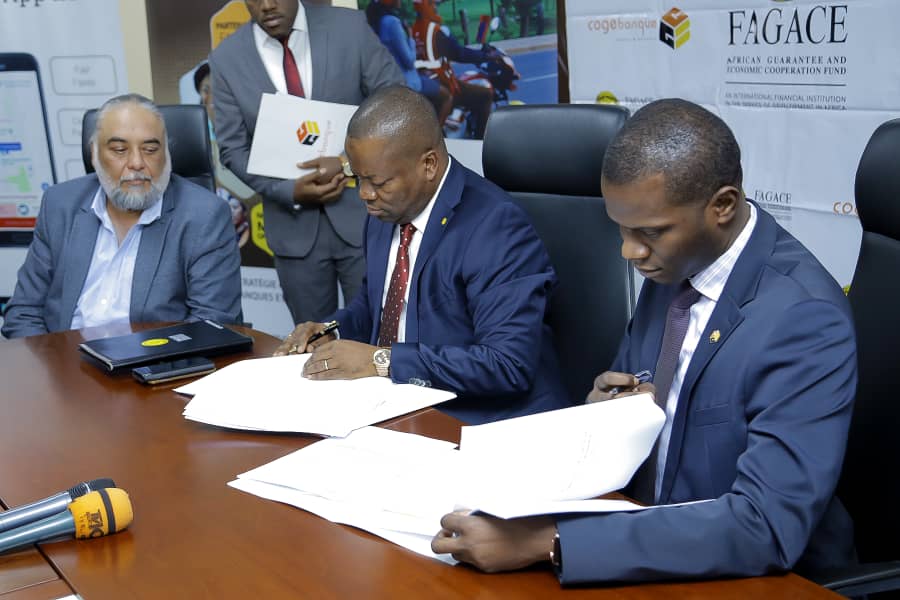 Umuyobozi Mukuru wa Cogebanque, Cherno Gaye (iburyo), Basile Tchakounte wa FAGACE (hagati) basoma ingingo zigize amasezerano mbere yo kuyashyiraho umukono. Umuyobozi Mukuru wa Yego Innovision, Karanvir Singh, yari abagaragiye