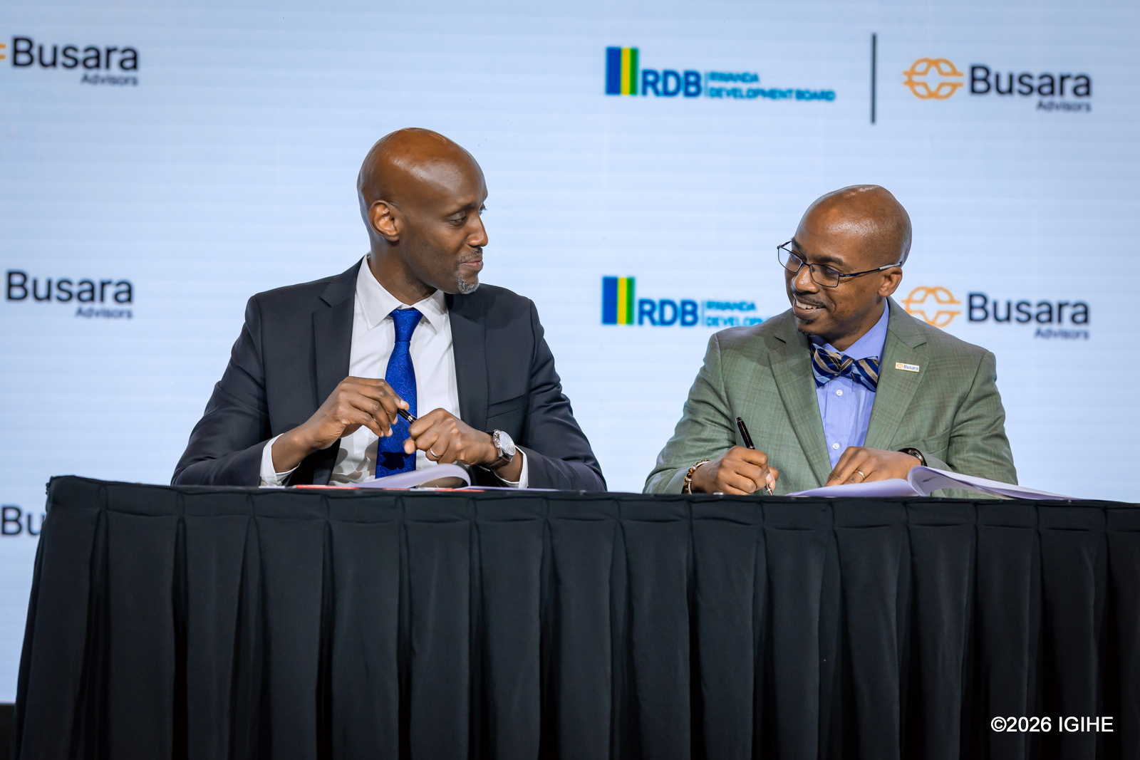 Jean-Guy Afrika na Perezida w’Inama wa Busara Advisors, Inc. bashyira umukono ku masezerano, Reuben E. Brigety II